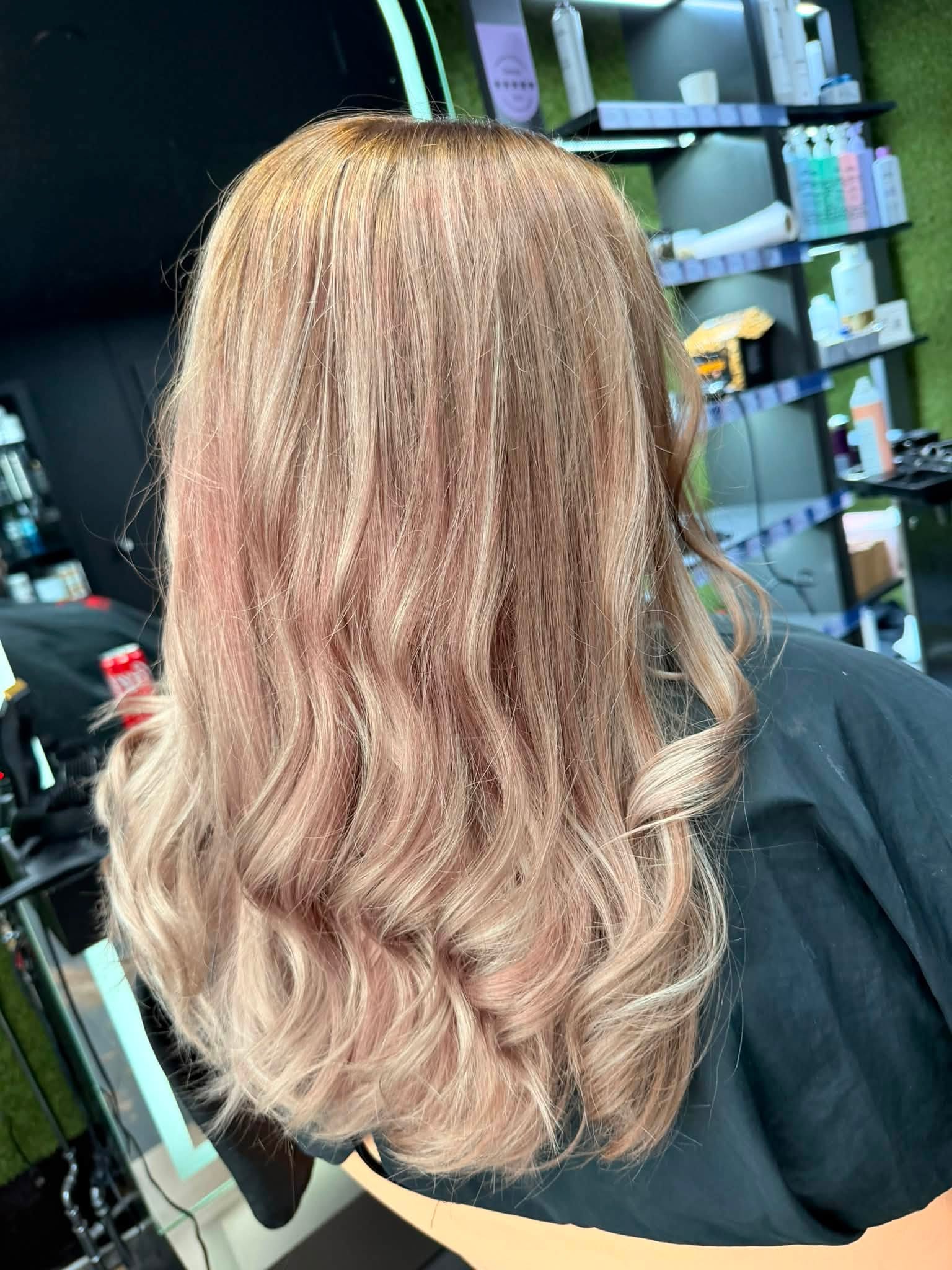 Pitkät, kevyesti laineelle laitetut hiukset, joissa vaaleanpunainen balayage-sävy.